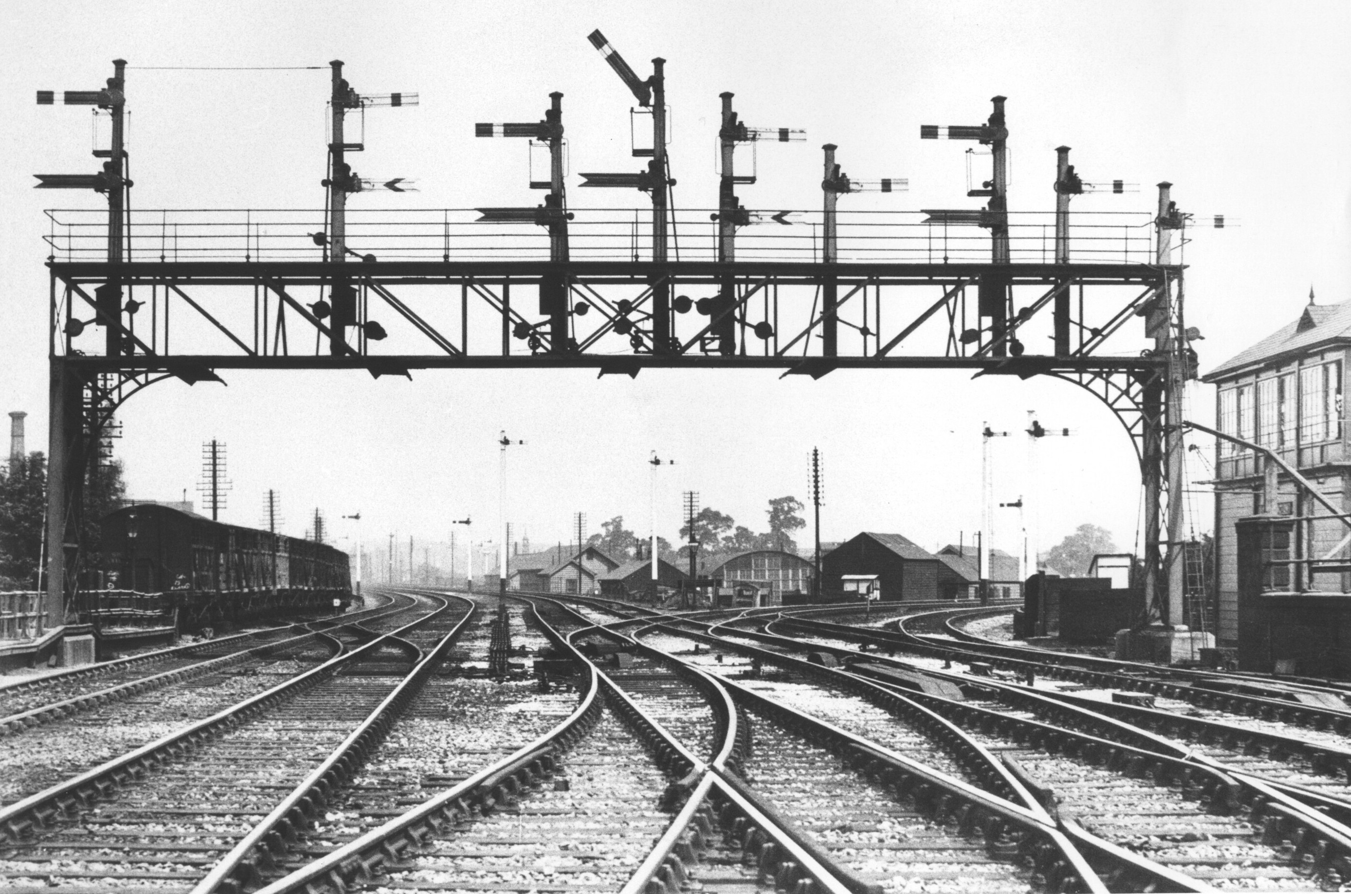 A photograph looking north from Derby station with Derby Junction signal box on the right and a signal gantry spanning five tracks, the lines to Chaddesden curving off to the right.